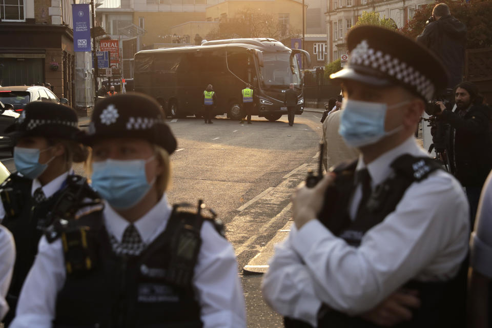 The buses carrying the Chelsea and Brighton teams arrive at Stamford Bridge stadium in London, protected by a police line, as fans protest against Chelsea's decision to be included amongst the clubs attempting to form a new European Super League, Tuesday, April 20, 2021. Reaction to the proposals from 12 clubs to rip up European soccer by forming a breakaway Super League has ranged from anger and condemnation to humor and sarcasm. (AP Photo/Matt Dunham)