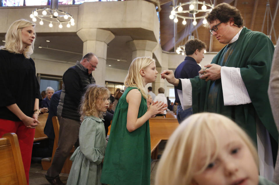 In this Feb. 9, 2020, photo, the Whitfield family, wife Alli, left, daughters Zoe-Catherine, 5, second from left, and Maggie, 9, second from right, receive communion from their dad and husband, The Rev. Joshua Whitfield, right, during Sunday Mass at St. Rita Catholic Community in Dallas. In 2009 the Whitfields, who were Episcopalian, converted to Catholicism. (AP Photo/Jessie Wardarski)