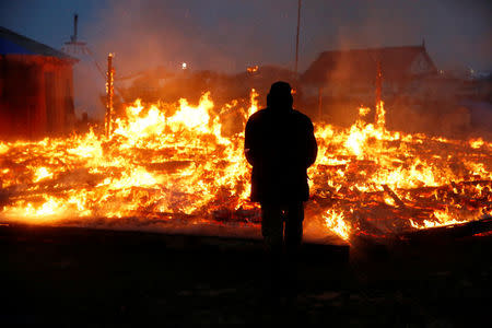 An opponent of the Dakota Access oil pipeline watches a building burn after it was set alight by protesters preparing to evacuate the main opposition camp against the pipeline near Cannon Ball, North Dakota, U.S., February 22, 2017. REUTERS/Terray Sylvester