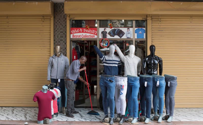 A trader cleans his boutique stall as he opens it after protests which disrupted business, in Addis Ababa