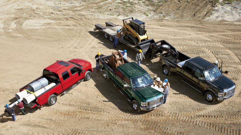 A photo of three Ford F-450 pickup trucks on a work site. 