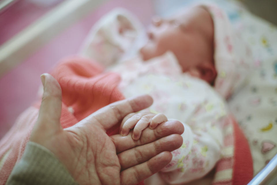 Newborn baby holding on to Mothers hand while in hospital.