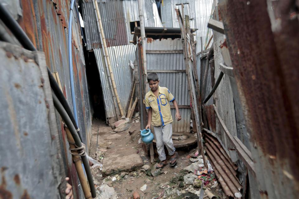 FILE - In this June 1, 2016, file photo, a Bangladeshi boy walks out of a toilet at a slum in Dhaka, Bangladesh. A new report by the United Nations children’s agency on Friday, April 5, 2019, says the lives and futures of more than 19 million Bangladeshi children are at risk from colossal impacts of devastating floods, cyclones and other environmental disasters linked to climate change. (AP Photo/A.M. Ahad, File)