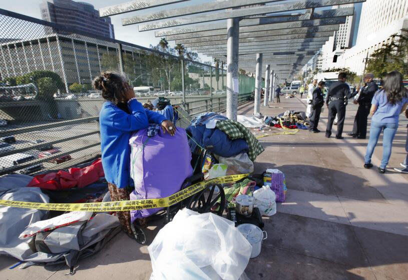 Ry Thounry packs up her tent on the Main Street overpass above the 101 Freeway in downtown Los Angeles while sanitation crews move in to clean the homeless encampment.