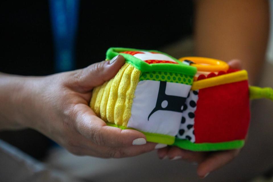 A hand holds colorful plush block toy