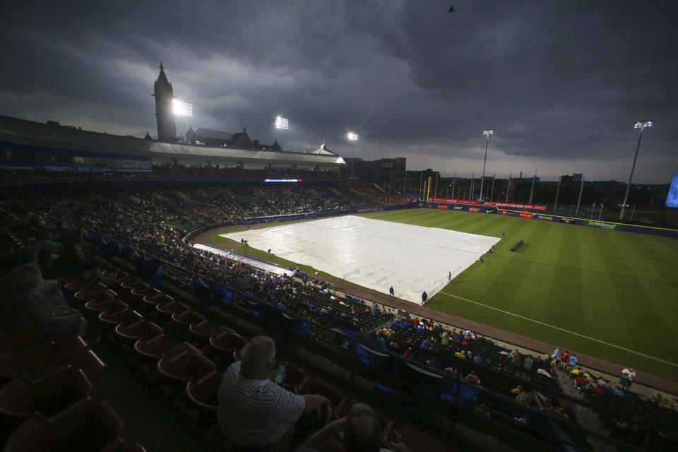 Fans watch as the grounds crew covers the infield with a tarp before the baseball game between the Toronto Blue Jays and Boston Red Sox on Tuesday, July 20, 2021, in Buffalo, N.Y. The game was postponed due to a thunderstorm in the area. (AP Photo/Joshua Bessex)