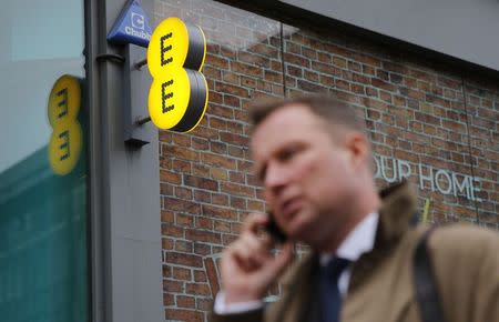 A pedestrian talks on the phone as he walks past an EE shop on Oxford Street in London, November 26, 2014. REUTERS/Suzanne Plunkett