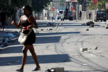 A woman walks in a street as Haitian National Police officers patrol after a march in Port-au-Prince. REUTERS/Andres Martinez Casares