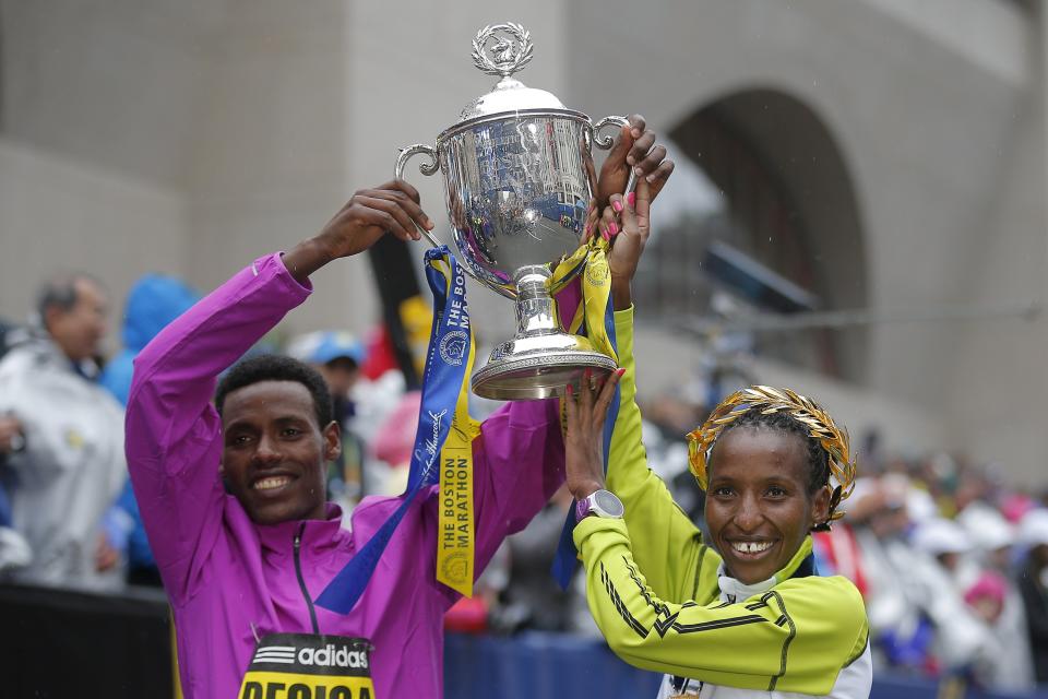 Men's division winner Lelisa Desisa of Ethiopia and women's division winner Caroline Rotich of Kenya pose with the trophy at the finish line of the 119th Boston Marathon in Boston