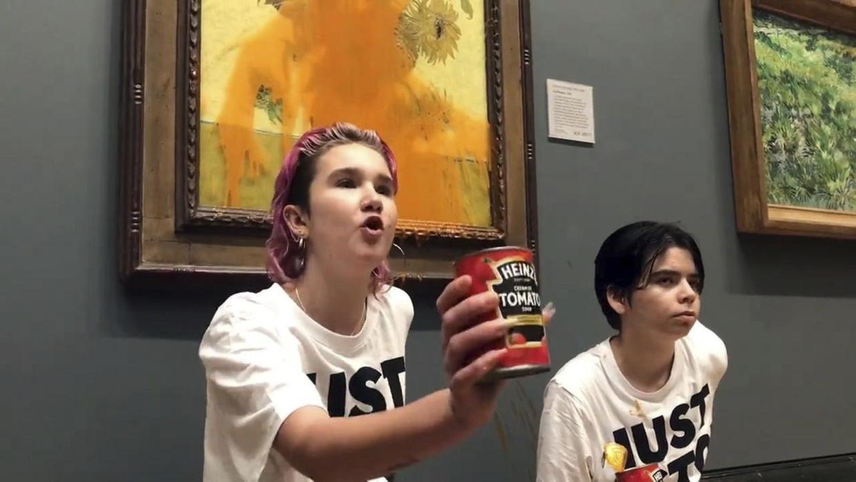 A handout photo issued by Just Stop Oil of two protesters who have thrown tinned soup at Vincent Van Gogh's famous 1888 work Sunflowers at the National Gallery in London, Friday Oct. 14, 2022. 