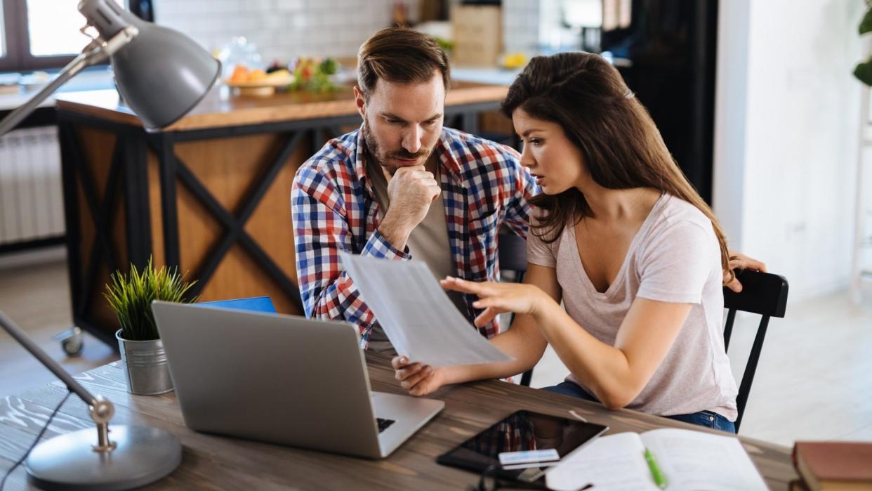 Frustrated couple checking bills at home using laptop.