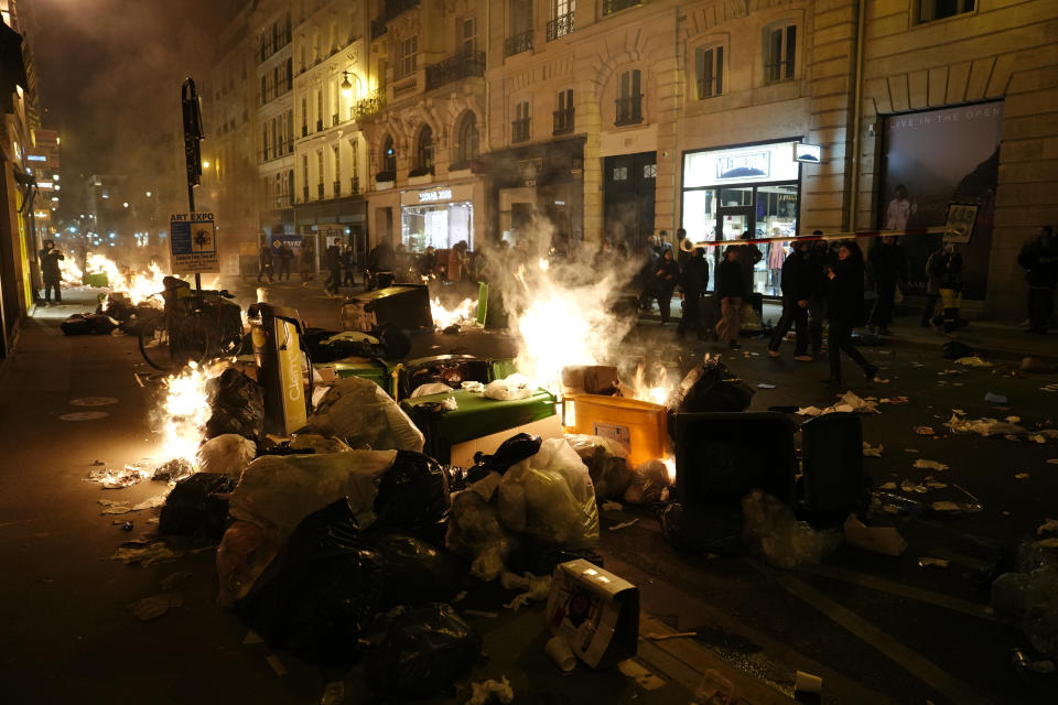 Garbage is set on fire by protesters after a demonstration near Concorde square, in Paris, Thursday, March 16, 2023. French President Emmanuel Macron has shunned parliament and imposed a highly unpopular change to the nation's pension system, raising the retirement age from 62 to 64. (AP Photo/Lewis Joly)