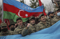 Azerbaijani soldiers with a national flag with the words "Lachin" celebrate the transfer of the Lachin region to Azerbaijan's control, as part of a peace deal that required Armenian forces to cede the Azerbaijani territories they held outside Nagorno-Karabakh, in Aghjabadi, Azerbaijan, Tuesday, Dec. 1, 2020. Azerbaijan has completed the return of territory ceded by Armenia under a Russia-brokered peace deal that ended six weeks of fierce fighting over Nagorno-Karabakh. Azerbaijani President Ilham Aliyev hailed the restoration of control over the Lachin region and other territories as a historic achievement. (AP Photo/Emrah Gurel)