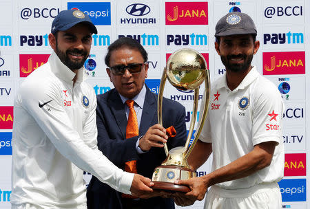 Cricket - India v Australia - Fourth Test cricket match - Himachal Pradesh Cricket Association Stadium, Dharamsala - 28/03/17 - India's Virat Kohli (L) and Ajinkya Rahane (R) receive the trophy from the former Indian cricket player Sunil Gavaskar after winning the series. REUTERS/Adnan Abidi