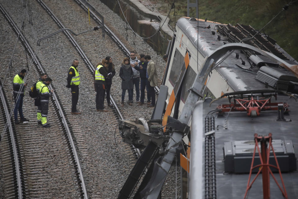 Police and railroad workers look at the derailed cars of a commuter train that went off the tracks near Barcelona, Spain, Tuesday, Nov. 20, 2018. Authorities in Spain say one person has died and six have been slightly injured when a landslide derailed the commuter train traveling toward Barcelona early on Tuesday. (AP Photo/Emilio Morenatti)