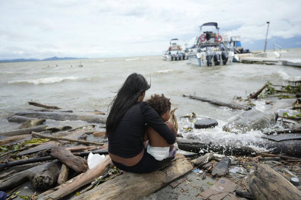 Venezuela migrant Yusney Velandia and her child watch boats that carry migrants to Acandi from Necocli, Colombia, Thursday, Oct. 13, 2022, as she considers continuing her journey north. Some Venezuelans are reconsidering their journey to the U.S. after the U.S. government announced on Oct. 12 that Venezuelans who walk or swim across the border will be immediately returned to Mexico without rights to seek asylum. (AP Photo/Fernando Vergara)