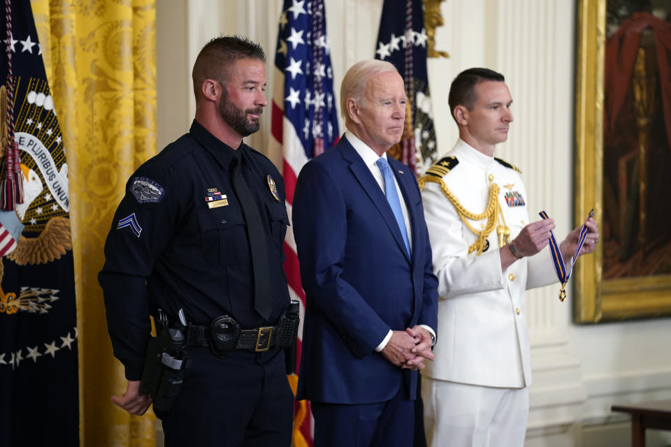 CORRECTS FROM LITTLETOWN TO LITTLETON - President Joe Biden listens before presenting the Medal of Valor, the nation's highest honor for bravery by a public safety officer, to Cpl. Jeffrey Farmer, of the Littleton, Colo., Police Dept., left, during an event in the East Room of the White House, Wednesday, May 17, 2023, in Washington. (AP Photo/Evan Vucci)