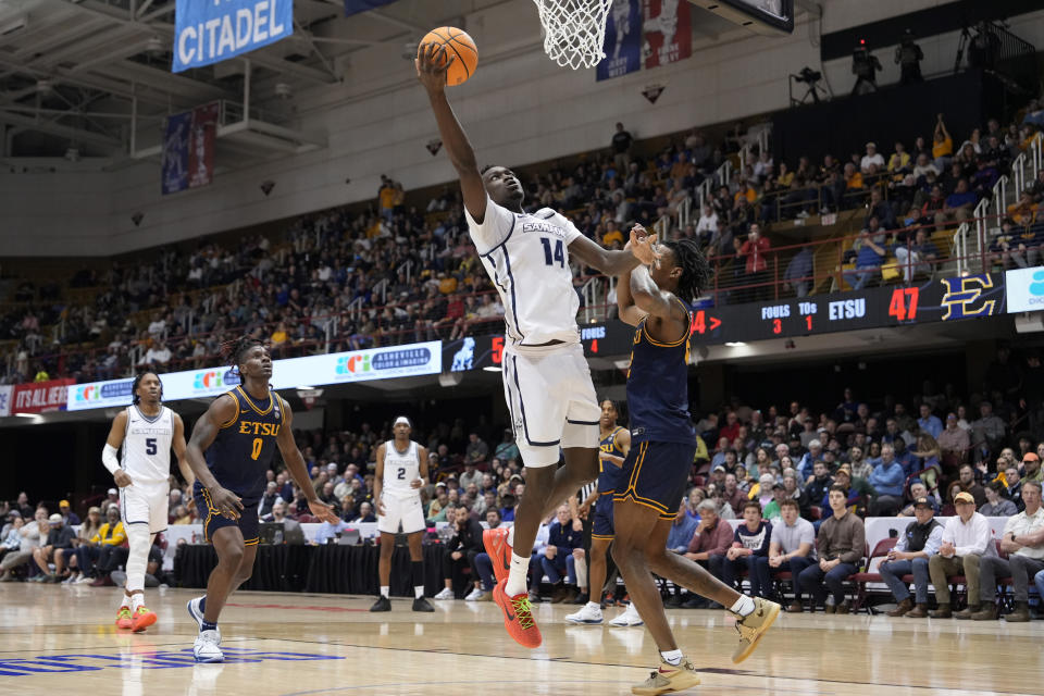 Samford forward Achor Achor (14) leaps to the basket over East Tennessee State forward Jaden Seymour, front right, during the second half of the NCAA college basketball championship game for the Southern Conference tournament, Monday, March 11, 2024, in Asheville, N.C. (AP Photo/Kathy Kmonicek)