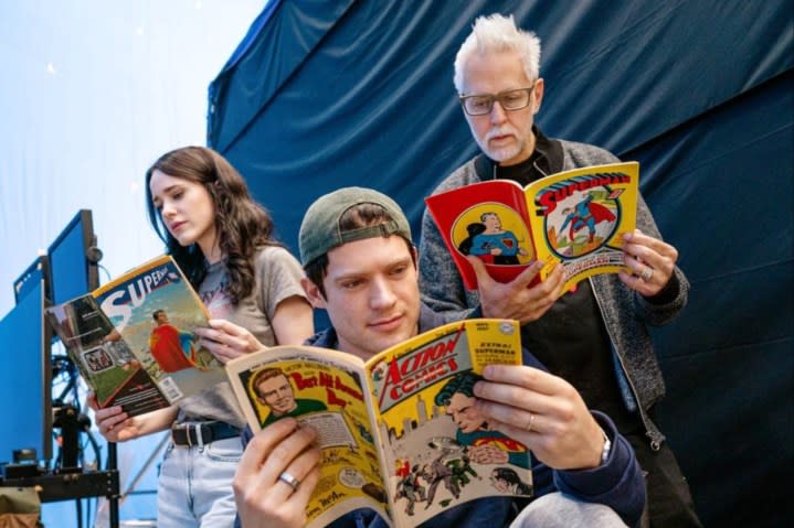 A woman and two males read Superman comics.