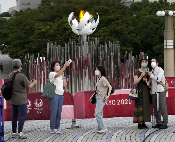 TOKYO, - JULY 30: People take selfies in front of the Olympic Cauldron. Below them a small homeless camp is located under the Tokyo Olympic Cauldron.Tokyo Olympics on Friday, July 30, 2021 in Tokyo, {stmens}. (Gary Ambrose / For the Times)