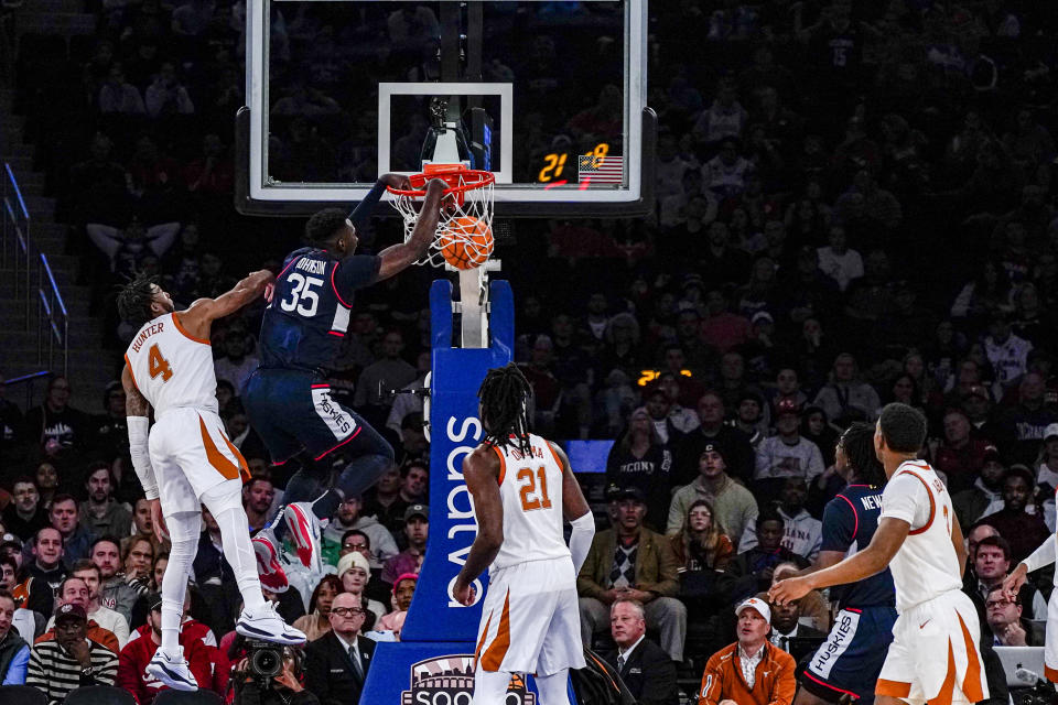 Connecticut forward Samson Johnson (35) dunks the ball while being defended by Texas guard Tyrese Hunter (4) during the first half of an NCAA college basketball game in the final of the Empire Classic tournament in New York, Monday, Nov. 20, 2023. (AP Photo/Peter K. Afriyie)