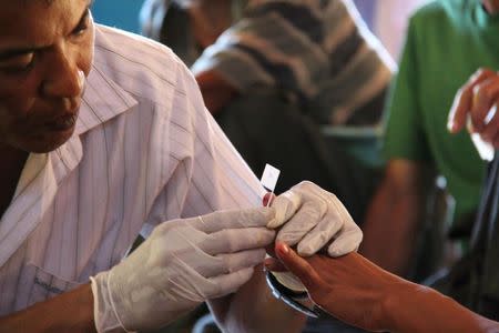 A government health worker takes a blood sample to be tested for malaria in Ta Gay Laung village hall in Hpa-An district in Kayin state, south-eastern Myanmar, November 28, 2014. REUTERS/Astrid Zweynert