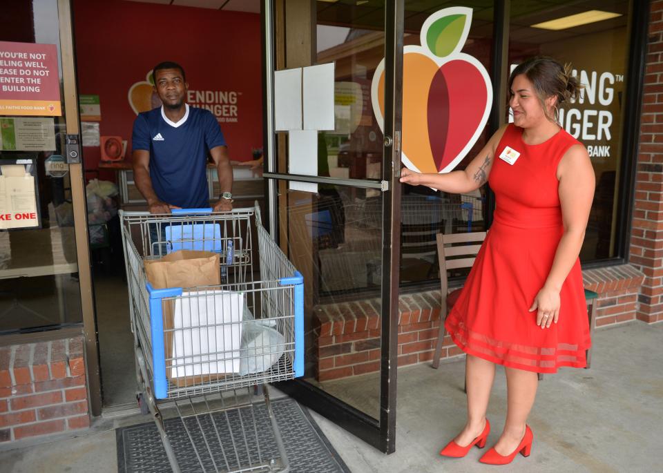Ana Reyes, right, site manager at the DeSoto Food and Resource Center in Arcadia, hold the door for Wasner Absolu of Arcadia, who had just picked up free groceries for the first time. 