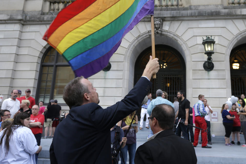 Same-sex marriage supporter Shon DeAmon holds a flag as his partner James Porter, right, watches at the Pulaski County Courthouse in Little Rock, Ark., Monday, May12, 2014. Monday was the first day marriage licenses were granted to same-sex couples in the county. (AP Photo/Danny Johnston)