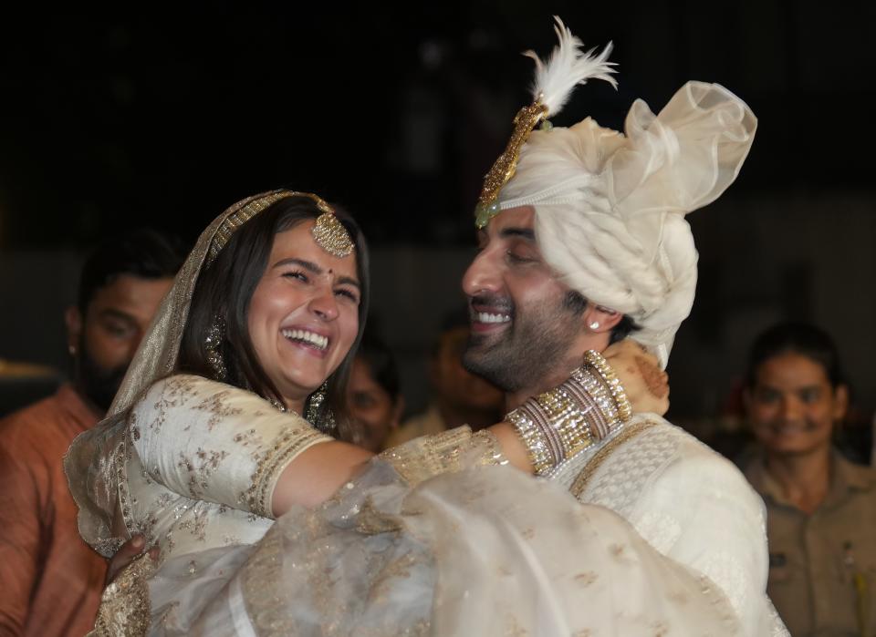 Bollywood actors Ranbir Kapoor, right and Alia Bhatt pose for photographs after their wedding outside their residence in Mumbai, India, Thursday, April 14, 2022. (AP Photo/Rajanish Kakade)