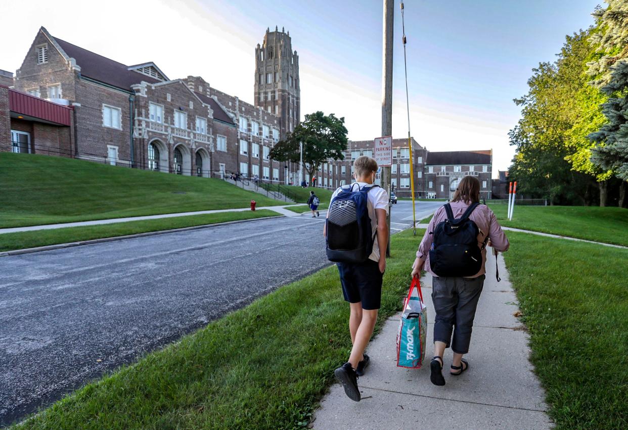 A student walks with a staffer to Manitowoc Lincoln High School on their way to the first day back to school, Monday, August 30, 2021, in Manitowoc, Wis.
