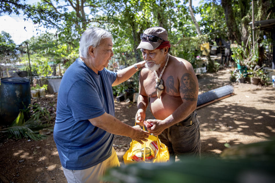 Leo Tudela, left, brings food for Everett Torregrosa as he visits his home in Hagatna, Guam, Thursday, May 9, 2019. "We're like brothers," said Torregrosa of Tudela who checks on him periodically after learning they each were victims of sexual abuse by priests when they were boys. (AP Photo/David Goldman)