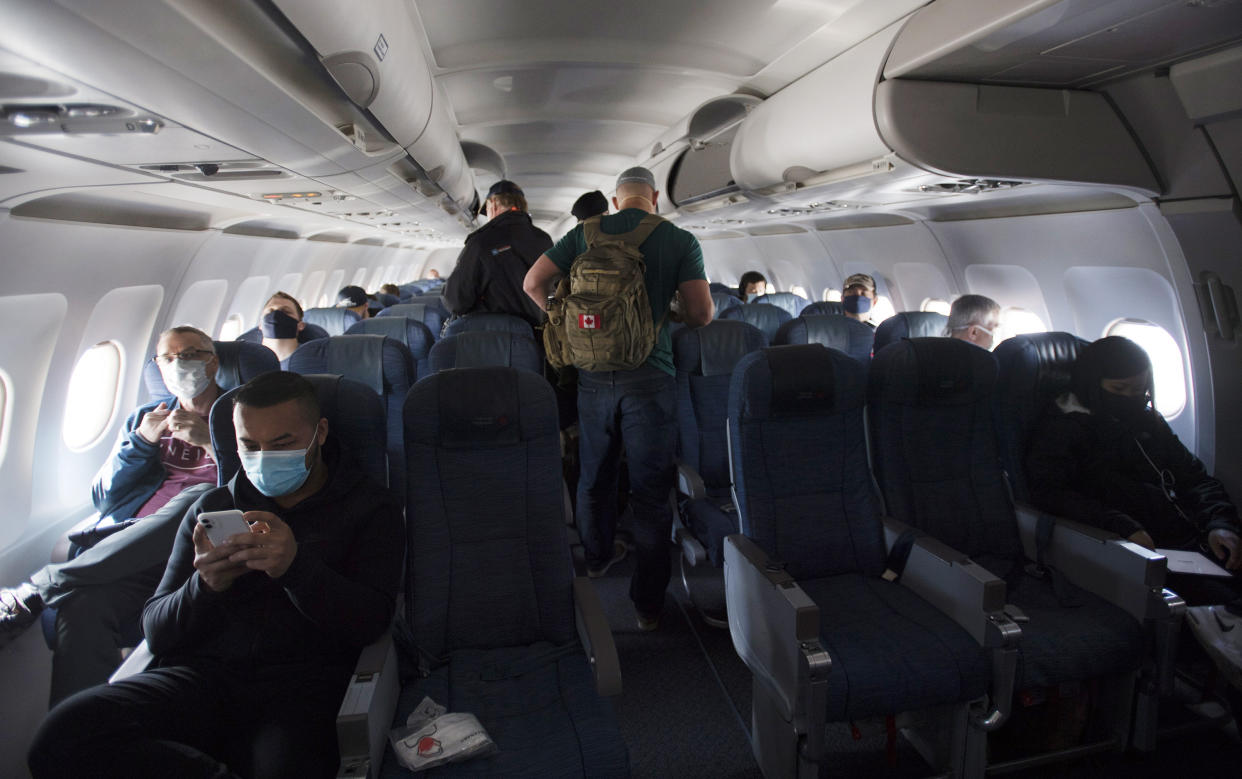 Passengers wear protective face masks and are physically distanced on a flight from Calgary to Vancouver, Tuesday, June 9, 2020. Airlines in Canada and around the world are suffering financially due to the lack of travel and travel bans due to COVID-19. (Jonathan Hayward/The Canadian Press via AP)