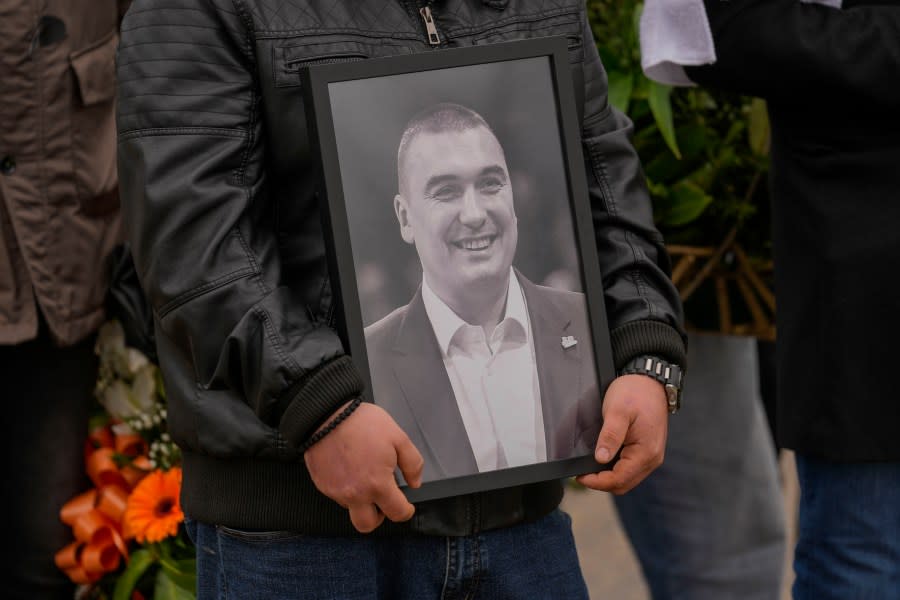 A man holds a photo of Golden State Warriors assistant coach Dejan Milojević during his funeral in Belgrade, Serbia, Monday, Feb. 12, 2024. Milojević, 46, died on Jan. 17, in Salt Lake City after heart attack. (AP Photo/Darko Vojinovic)