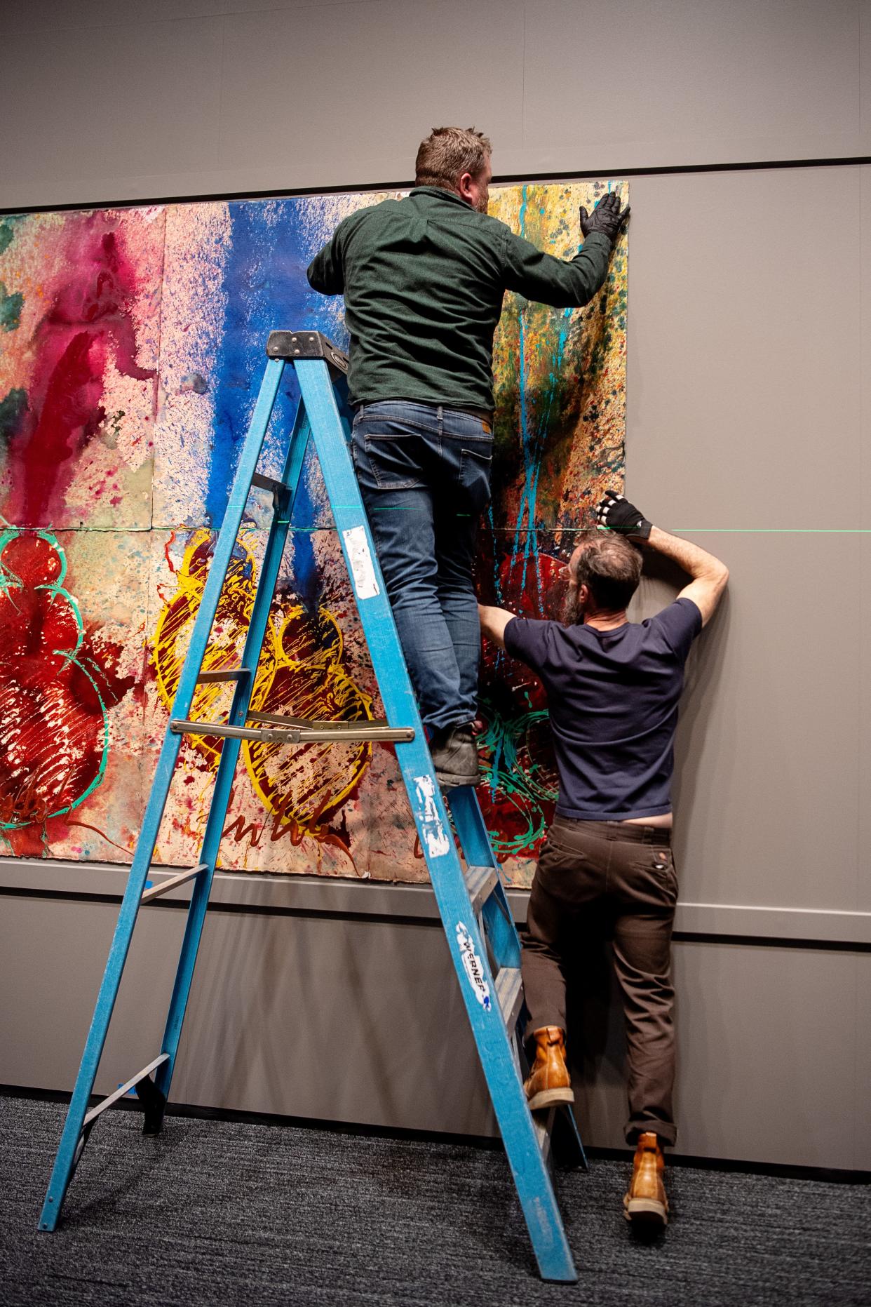 Chihuly Studio's Rick Holland, exhibition lead, left, and Alex Scott, art installer and assistant, place a panel of a mural onto the wall as they install the Chihuly exhibit at Amherst on the Biltmore Estate, March 20, 2024.