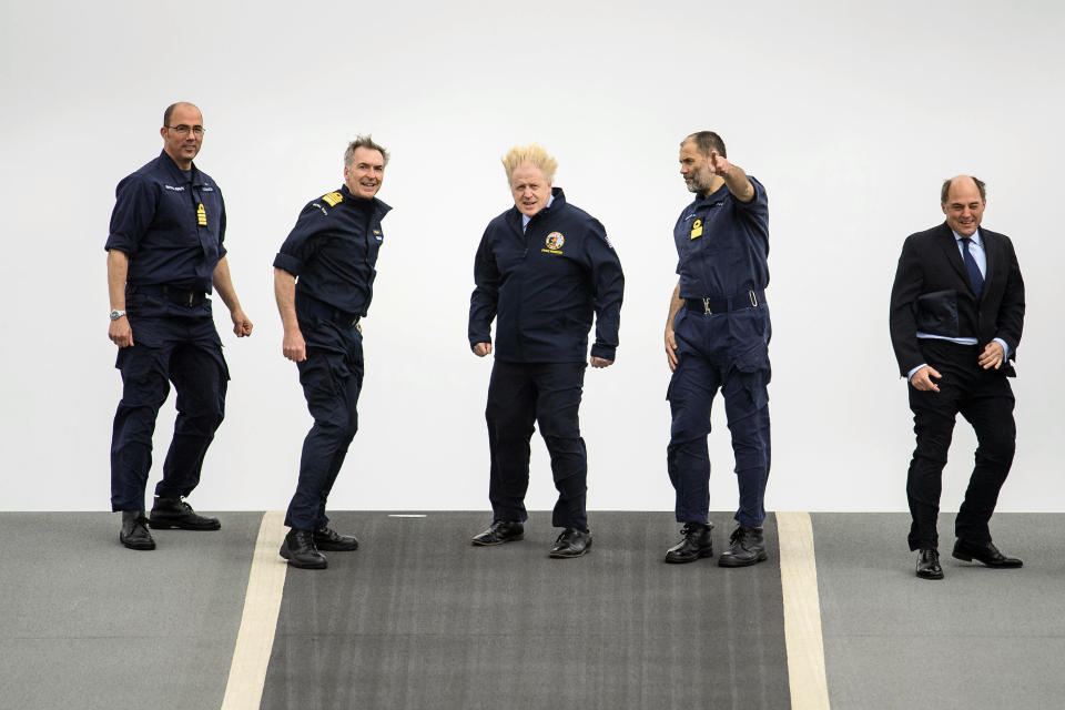 From left, Captain Angus Essenhigh, First Sea Lord Admiral Tony Radakin, Prime Minister Boris Johnson, Commodore Steve Moorhouse and Defence Secretary Ben Wallace face strong winds as they walk on the flight deck, during a visit aboard HMS Queen Elizabeth in Portsmouth, England, Friday, May 21, 2021 ahead of its first operational deployment to the Far East. (Leon Neal/Pool Photo via AP)