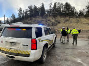 Sheriff deputies block a road in the town of Bailey, Colo., where authorities found an abandoned car that belonged to the suspect in a shooting of two administrators at a Denver high school, Wednesday, March 22, 2023. (AP Photo/Thomas Peipert)