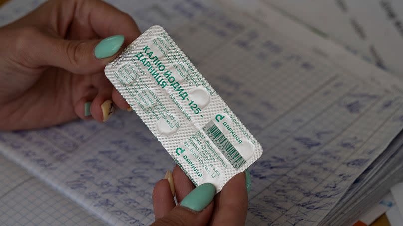 Eine Frau zeigt eine Packung Jodtabletten, bevor sie diese an die Bewohner einer Schule für den Fall eines Strahlungslecks in Saporischschja, Ukraine, verteilt.