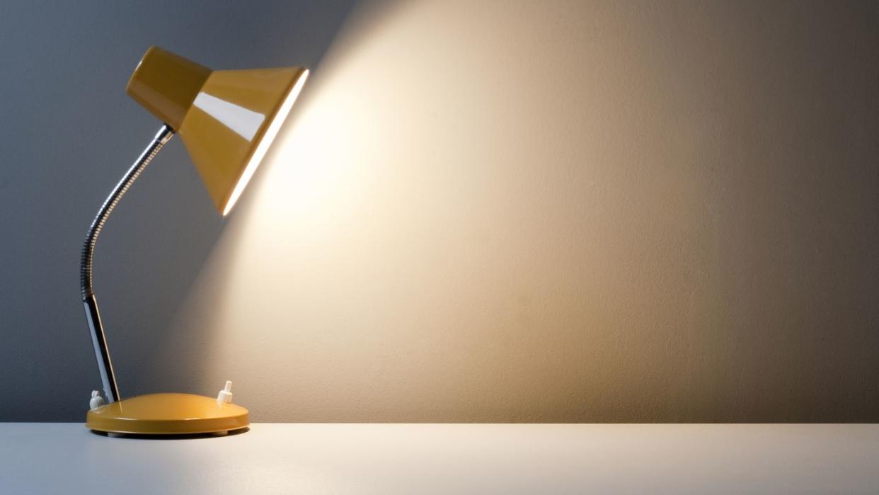 profile of yellow desk lamp, turned on on white table