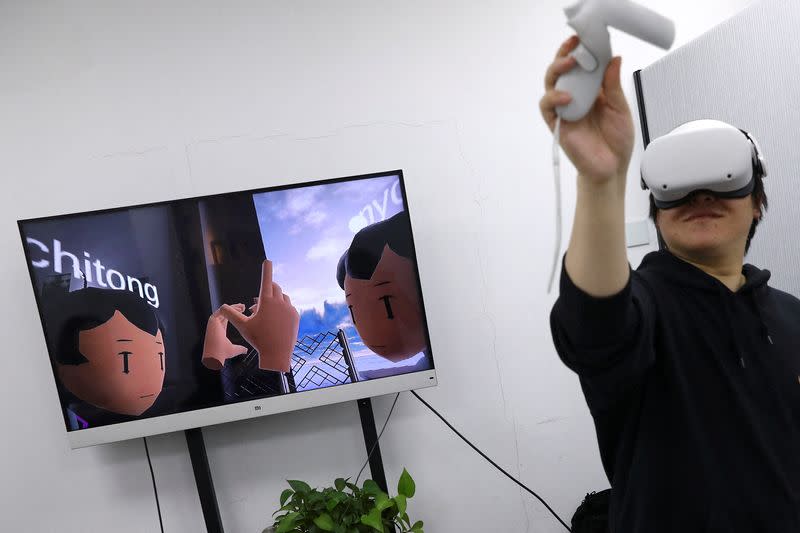 Pan Bohang, founder of vHome, a VR social gaming platform, wearing VR goggles greets with a user during a virtual gathering, at an office in Beijing