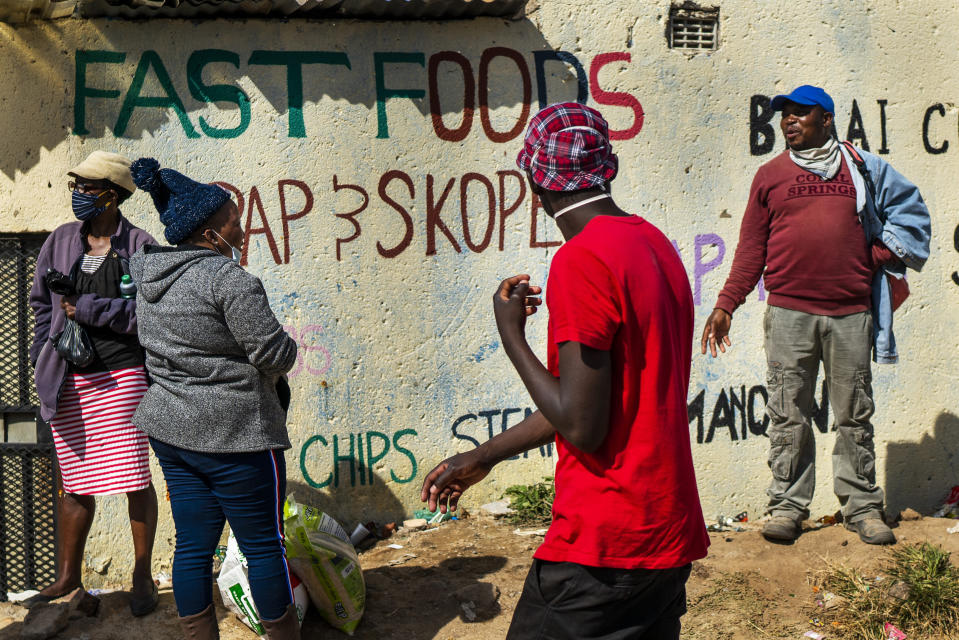 People line up to receive food handouts in the Olievenhoutbos township of Midrand, South Africa, Saturday May 2, 2020. though South Africa begun a phased easing of its strict lockdown measures on May 1, its confirmed cases of coronavirus continue to increase. (AP Photo/Jerome Delay)