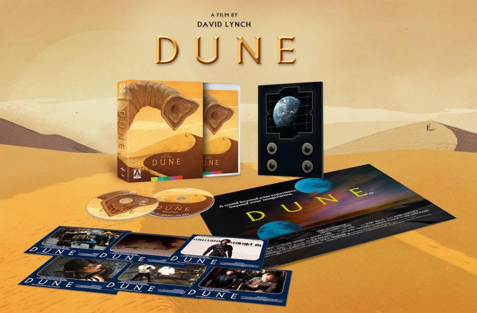 An open 4K box set of Dune, with posters postcards, blu-ray discs, a book, and poster all against a desert background