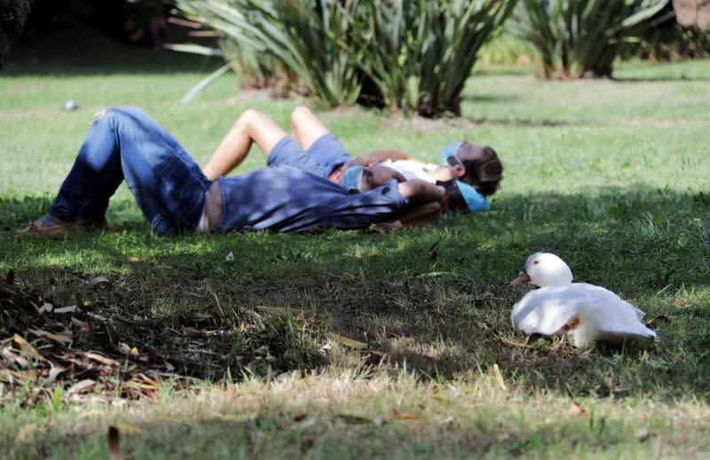 Students, wearing protective face masks, lie on the grass at the Universite Cote d'Azur in Nice