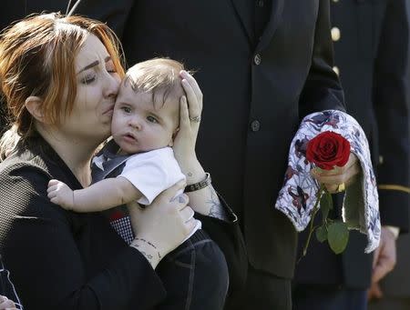 FILE PHOTO: Widow Alexandra McClintock holds her son Declan during a burial service for her husband, U.S. Army Sergeant First Class Matthew McClintock, who was killed in action in January at Arlington National Cemetery in Virginia March 7, 2016. REUTERS/Gary Cameron/File Photo