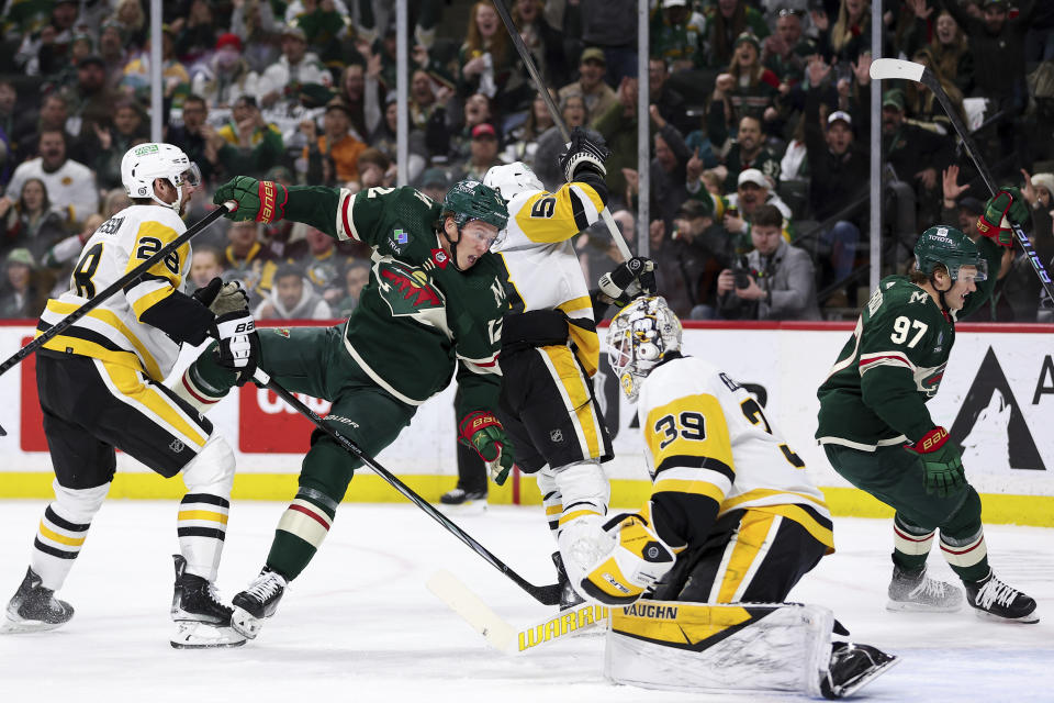 Minnesota Wild left wing Matt Boldy, middle left, reacts after scoring a goal past Pittsburgh Penguins goaltender Alex Nedeljkovic (39) while Penguins defenseman Marcus Pettersson (28) and defenseman Kris Letang (58) watch during the first period of an NHL hockey game Friday, Feb. 9, 2024, in St. Paul, Minn. (AP Photo/Matt Krohn)