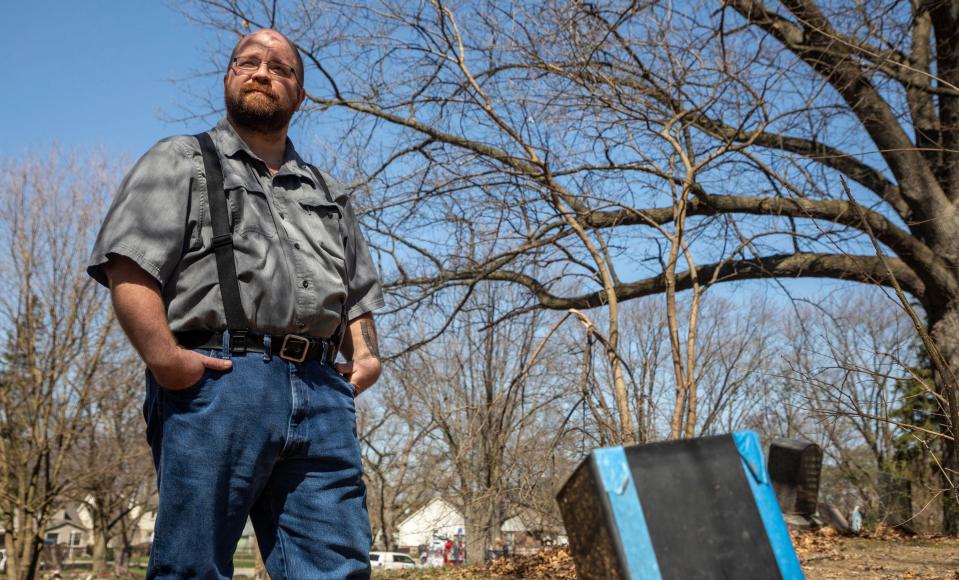 Chris Land, 41, stands next to a box with a label from the Tri-County Cremation Services, which he found sitting on top of a dirt hill inside the Oak Grove Burying Ground in Taylor on Wednesday, April 12, 2023. 