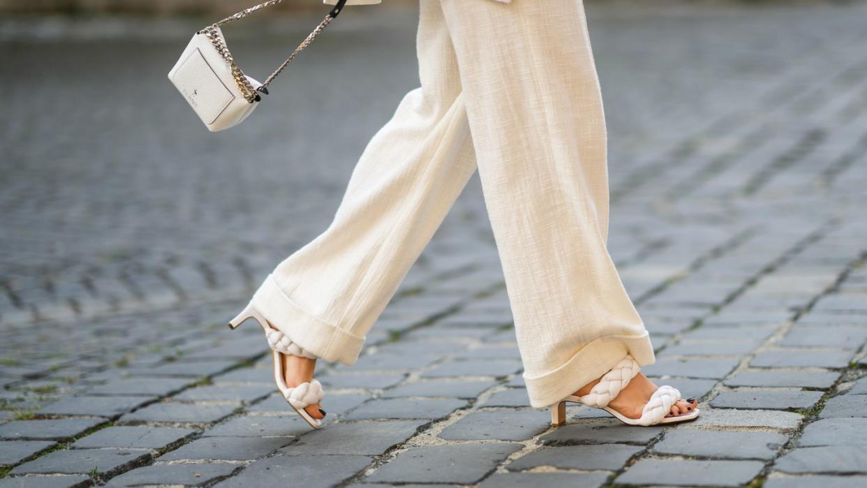 a street style photo of a woman wearing a cream monochrome outfit with black nail polish