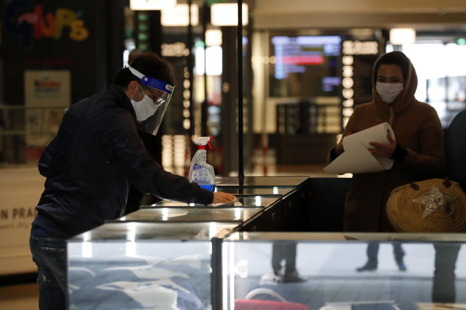 Employees clean their desk in a shopping mall Monday, May 11, 2020 in Paris. The French began leaving their homes and apartments for the first time in two months without permission slips as the country cautiously lifted its lockdown. Clothing stores, coiffures and other businesses large and small were reopening on Monday _ with strict precautions to keep the coronavirus at bay. (AP Photo/Francois Mori)