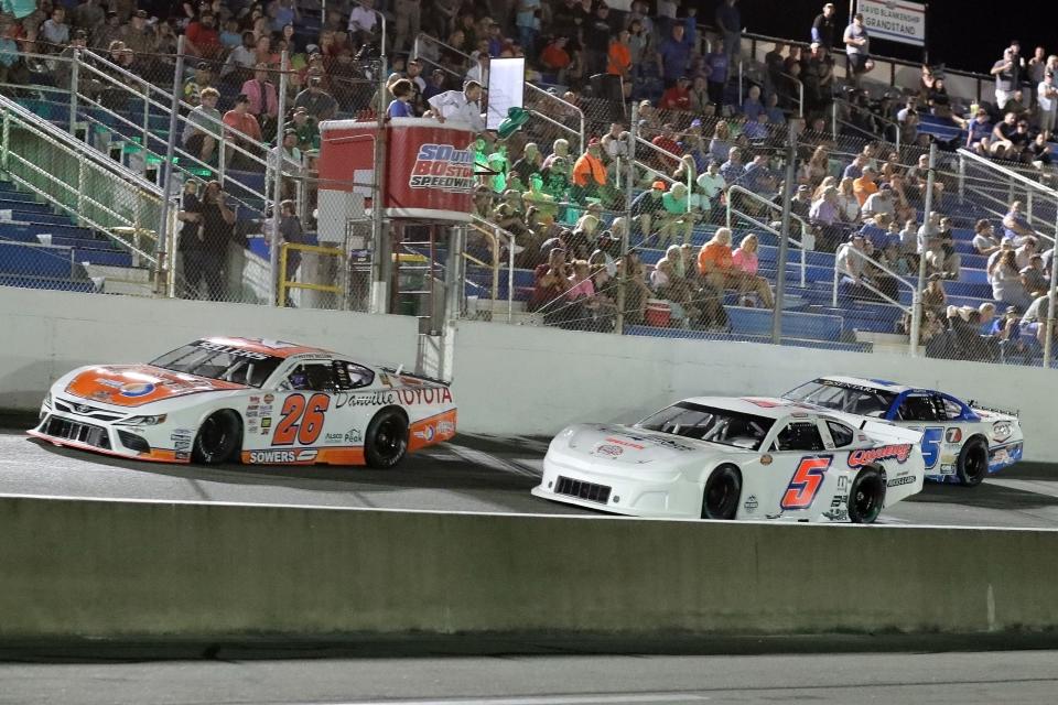 Peyton Sellers (26) fends off a challenge from Carter Langley (5) and Jacob Borst (25) as they speed down the frontstretch during the 100-lap Sentara Health Late Model Stock Car Division race that was part of the Italian Delight Family Restaurant Night Race at South Boston Speedway on Aug. 19, 2023. (Joe Chandler/South Boston Speedway)