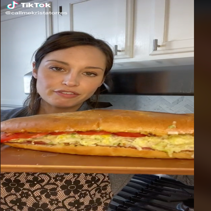 Krista holding up the large sandwich on a board