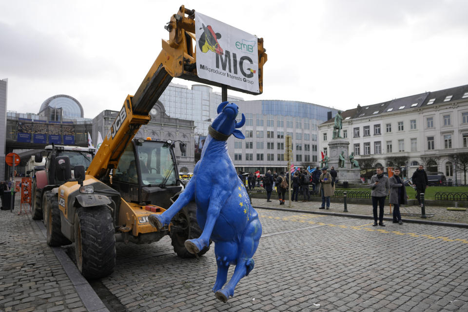 A plastic cow painted with the colors of the EU flag is held up by a strap from a tractor during a demonstration of French and Belgian farmers outside the European Parliament in Brussels, Wednesday, Jan. 24, 2024. (AP Photo/Virginia Mayo)